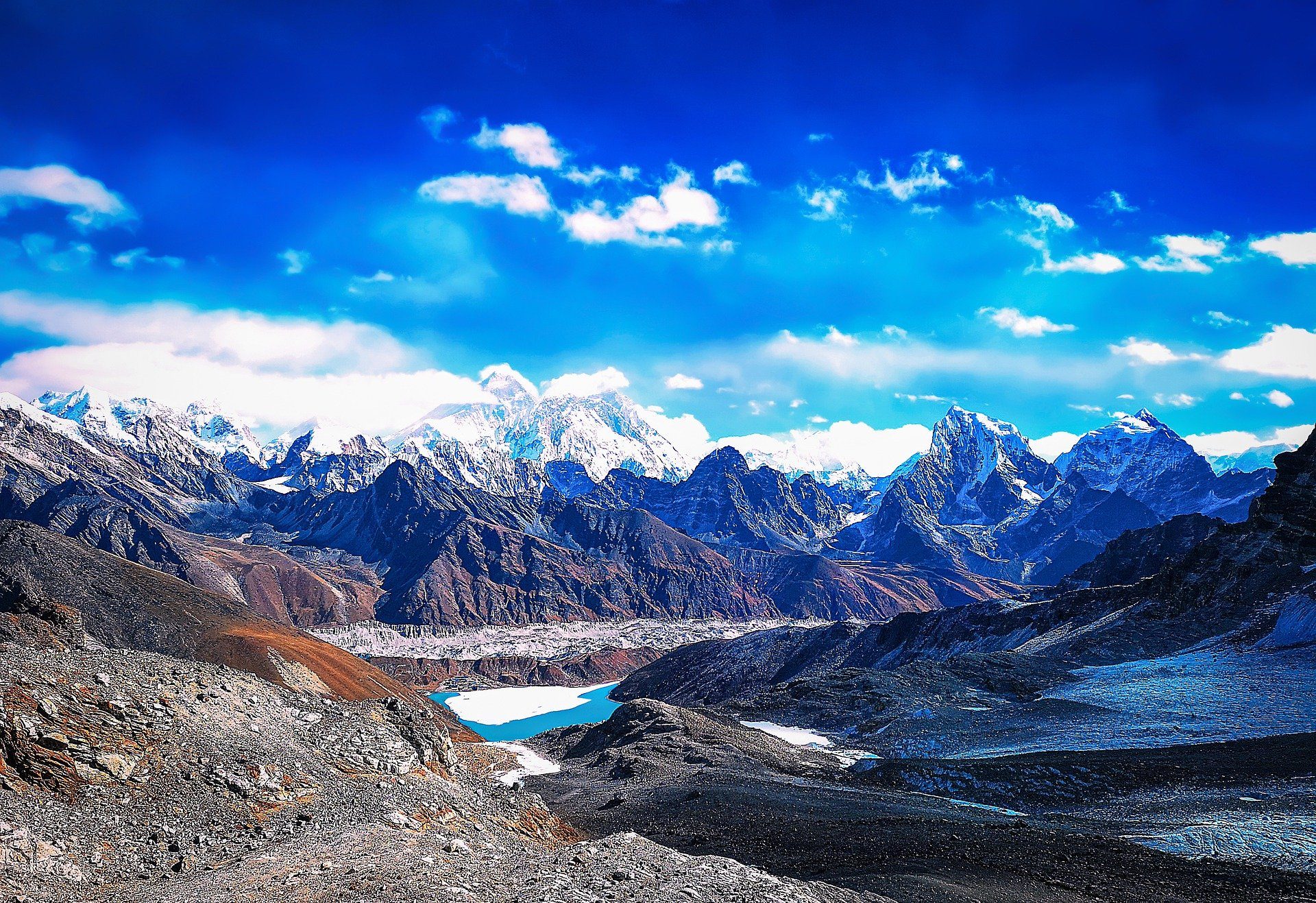 High-altitude glacial valley with a turquoise lake below snow-capped Himalayan peaks