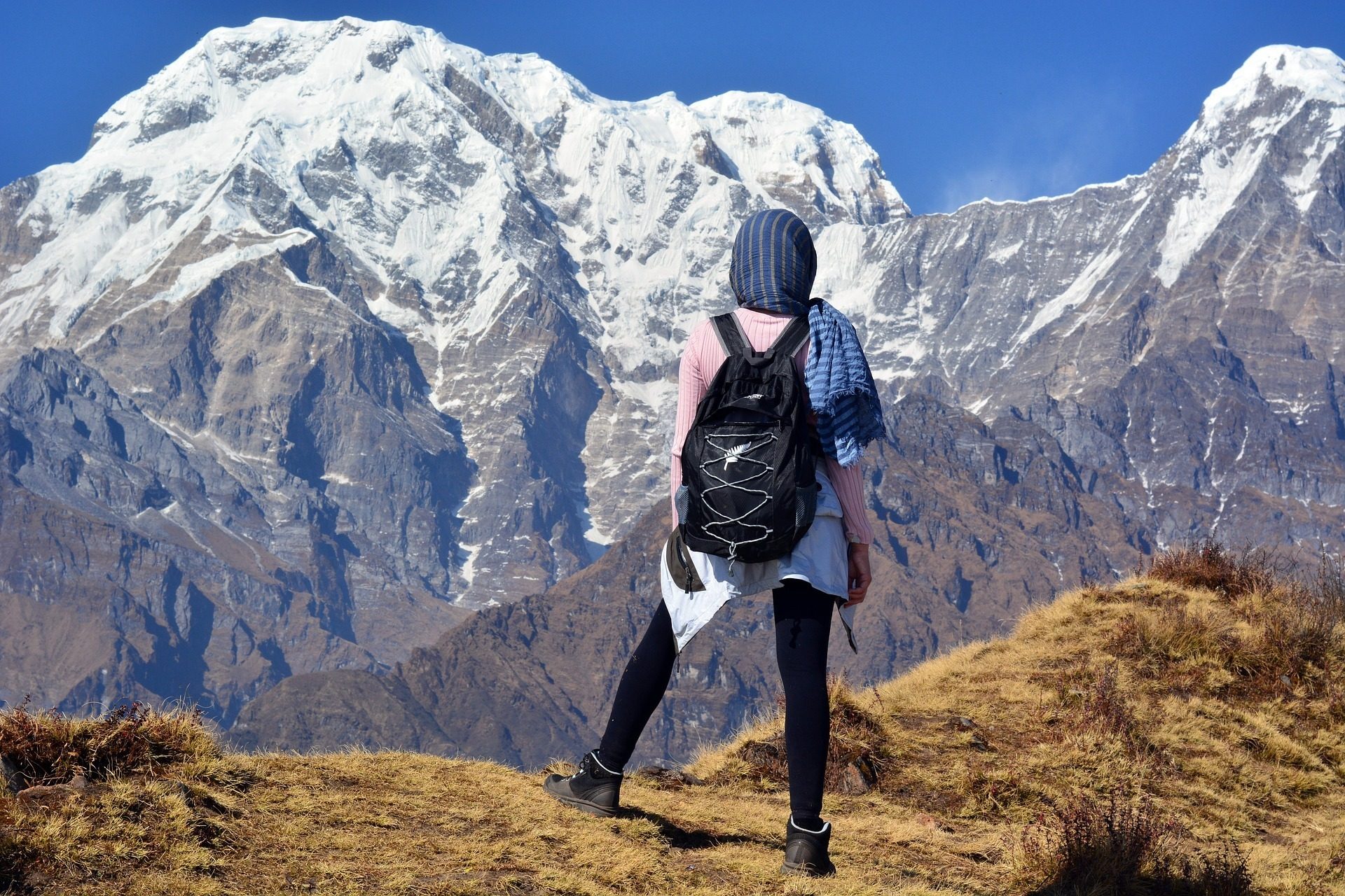 Trekker seen from behind looking out at a large snow-covered Himalayan peak