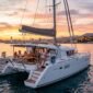 A wooden catamaran sailing the Mediterranean at sunset