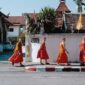 monks walking near wall beside street
