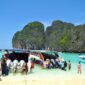 a group of people standing on a beach next to a boat
