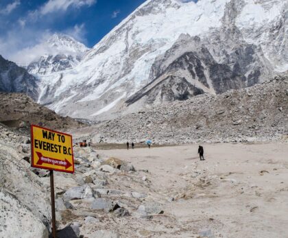 Yellow 'Way to Everest B.C.' sign on the Khumbu Glacier moraine with Everest region peaks behind