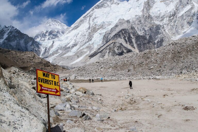 Yellow 'Way to Everest B.C.' sign on the Khumbu Glacier moraine with Everest region peaks behind